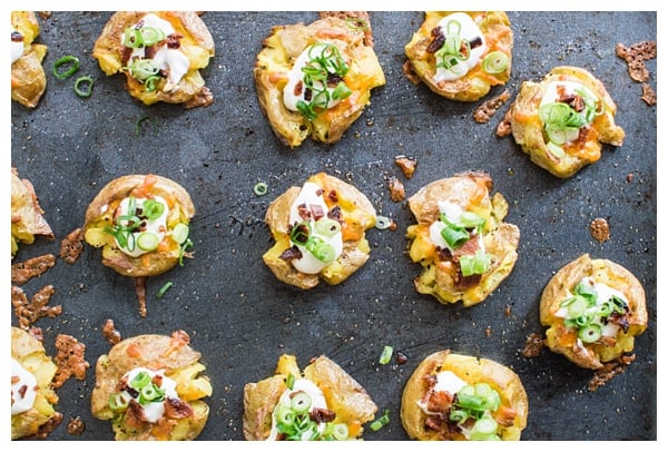 Loaded Smashed Potatoes -- crispy smashed potatoes topped with cheddar cheese, bacon, sour cream, and scallions. A fun side dish or perfect party appetizer!