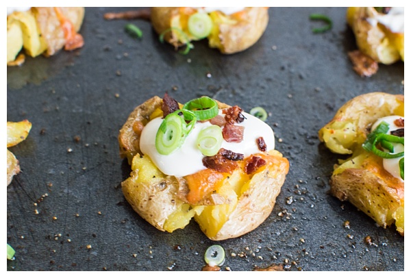 Loaded Smashed Potatoes -- crispy smashed potatoes topped with cheddar cheese, bacon, sour cream, and scallions. A fun side dish or perfect party appetizer!