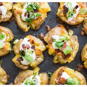 Loaded Smashed Potatoes -- crispy smashed potatoes topped with cheddar cheese, bacon, sour cream, and scallions. A fun side dish or perfect party appetizer!