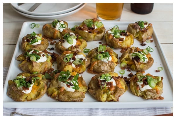 Loaded Smashed Potatoes -- crispy smashed potatoes topped with cheddar cheese, bacon, sour cream, and scallions. A fun side dish or perfect party appetizer!