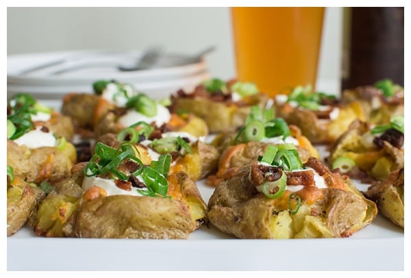 Loaded Smashed Potatoes -- crispy smashed potatoes topped with cheddar cheese, bacon, sour cream, and scallions. A fun side dish or perfect party appetizer!