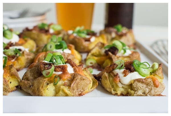 Loaded Smashed Potatoes -- crispy smashed potatoes topped with cheddar cheese, bacon, sour cream, and scallions. A fun side dish or perfect party appetizer!