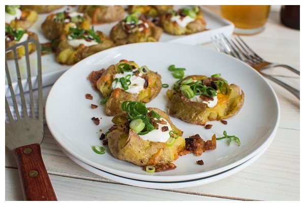 Loaded Smashed Potatoes -- crispy smashed potatoes topped with cheddar cheese, bacon, sour cream, and scallions. A fun side dish or perfect party appetizer!