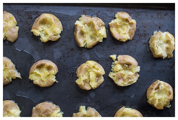 Loaded Smashed Potatoes -- crispy smashed potatoes topped with cheddar cheese, bacon, sour cream, and scallions. A fun side dish or perfect party appetizer!