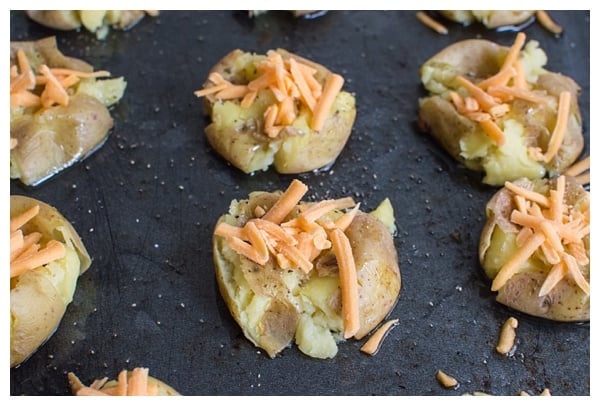 Loaded Smashed Potatoes -- crispy smashed potatoes topped with cheddar cheese, bacon, sour cream, and scallions. A fun side dish or perfect party appetizer!