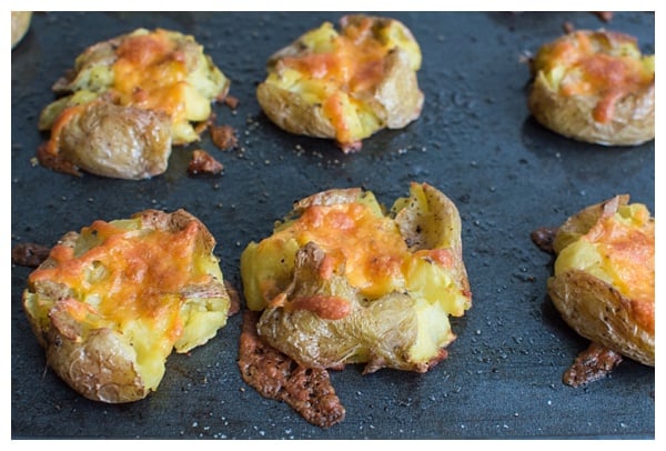 Loaded Smashed Potatoes -- crispy smashed potatoes topped with cheddar cheese, bacon, sour cream, and scallions. A fun side dish or perfect party appetizer!