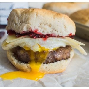 Sweet and Spicy Breakfast Sandwich with sausage, white cheddar, a fried egg, and raspberry preserves. Served on a buttermilk biscuit!