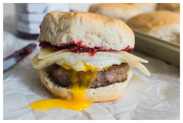 Sweet and Spicy Breakfast Sandwich with sausage, white cheddar, a fried egg, and raspberry preserves. Served on a buttermilk biscuit!